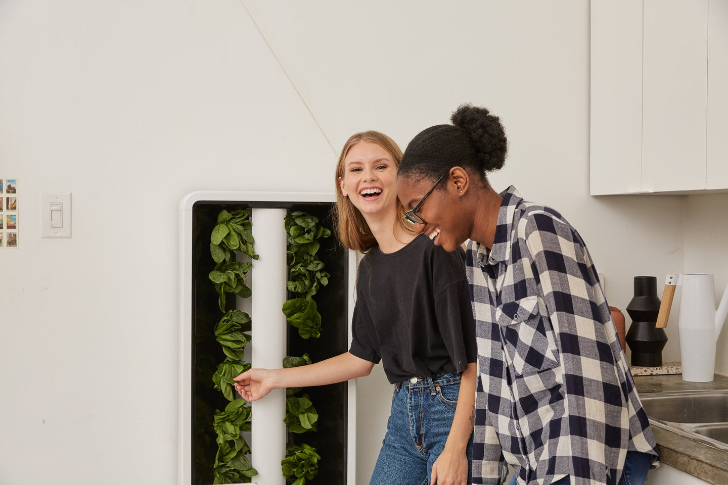 Two woman laughing because they're happy being around the beautiful indoor vertical farm they own. 